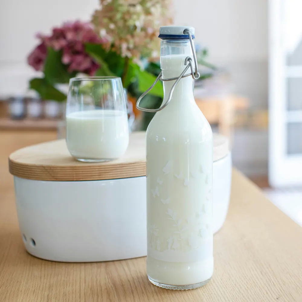 Bouteille et verre de kéfir sur une table de cuisine en bois clair